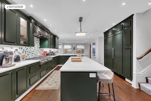 kitchen with stainless steel gas cooktop, dark wood finished floors, a peninsula, light countertops, and green cabinets