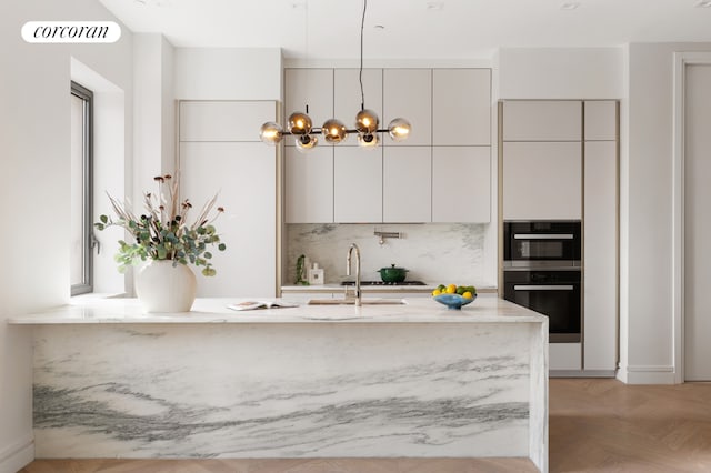 kitchen featuring light parquet floors, an inviting chandelier, tasteful backsplash, hanging light fixtures, and sink