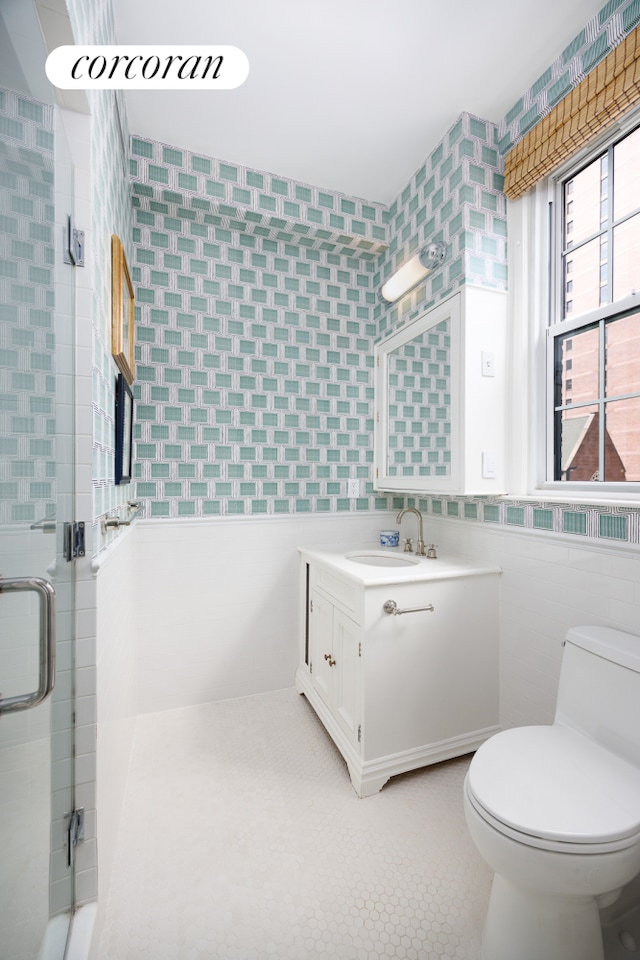bathroom with toilet, tile walls, a shower stall, and vanity