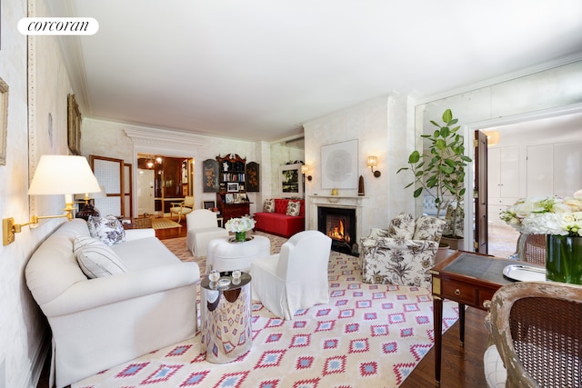 living room with ornamental molding, wood finished floors, a lit fireplace, and wallpapered walls