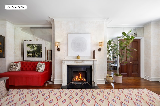 living area with crown molding, a fireplace with flush hearth, and wood finished floors