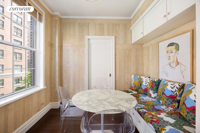 dining space featuring wooden walls, ornamental molding, and dark wood-type flooring