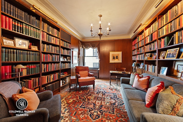 living area featuring built in features, crown molding, a notable chandelier, and wooden walls