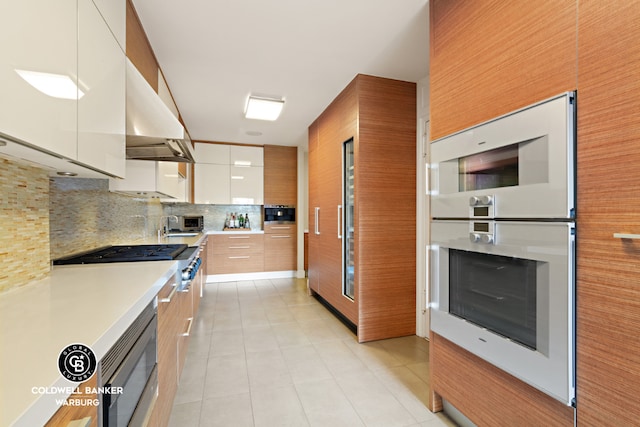 kitchen with light tile patterned floors, ventilation hood, stainless steel appliances, decorative backsplash, and white cabinets