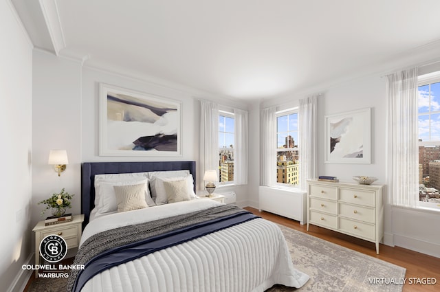 bedroom with ornamental molding, hardwood / wood-style floors, and radiator heating unit