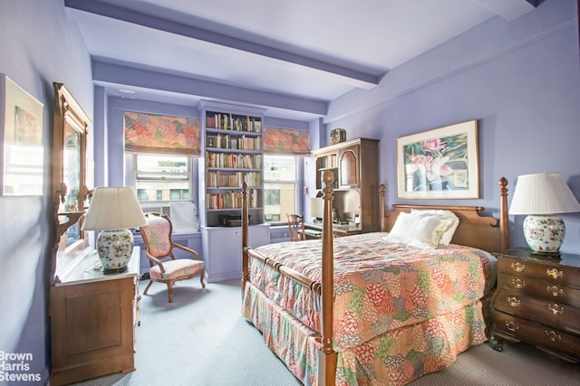 bedroom with beam ceiling and light colored carpet