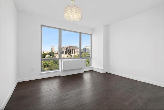 spare room featuring dark hardwood / wood-style floors and an inviting chandelier