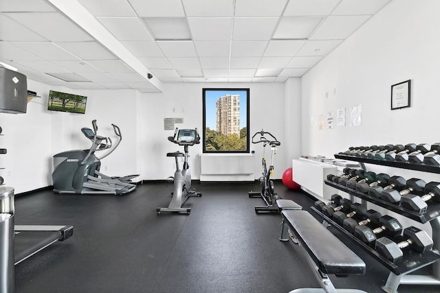 exercise room with baseboard heating and a drop ceiling