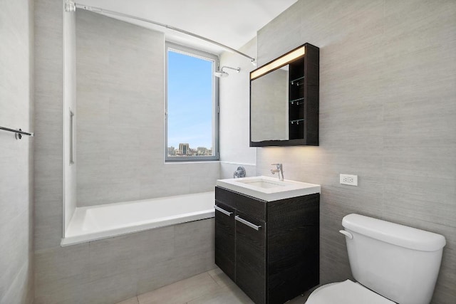 full bathroom featuring toilet, vanity, tile walls, tile patterned floors, and tiled shower / bath combo