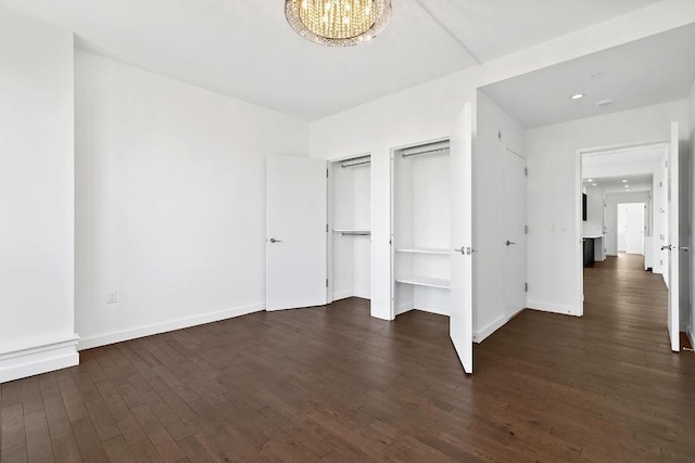 unfurnished bedroom featuring dark wood-type flooring and a chandelier