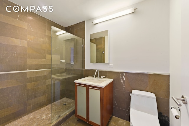 full bathroom featuring tile walls, tiled shower, toilet, and vanity