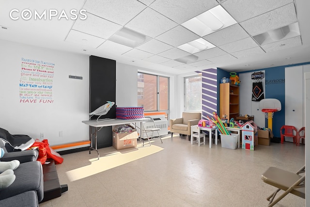 recreation room with a paneled ceiling, baseboards, and tile patterned floors