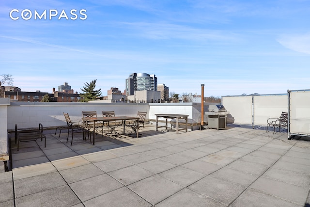 view of patio with a grill, a view of city, and outdoor dining area