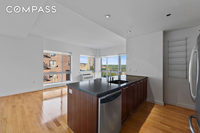kitchen featuring stainless steel appliances, dark countertops, a sink, light wood-style flooring, and recessed lighting