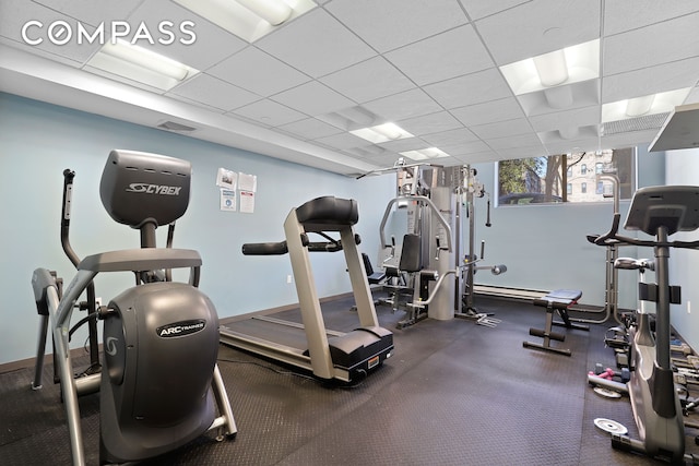 exercise room featuring a paneled ceiling, visible vents, and baseboards