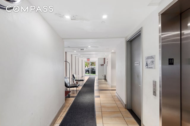 corridor featuring light tile patterned floors and elevator