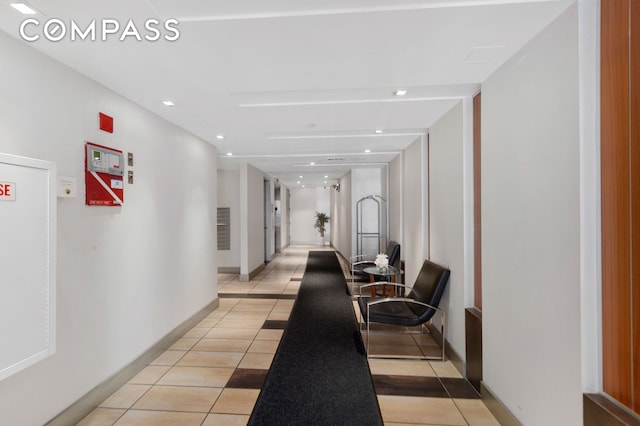 hallway featuring baseboards, light tile patterned flooring, and recessed lighting
