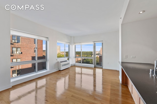 interior space with radiator, light wood-style flooring, baseboards, and recessed lighting