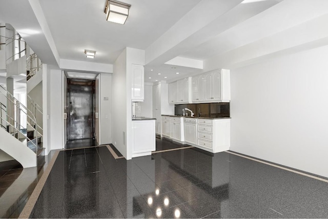 interior space with sink, white cabinets, and backsplash