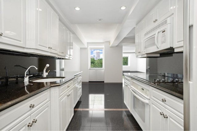 kitchen with sink, white cabinets, white appliances, and dark stone counters