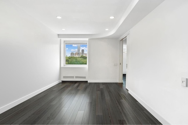 unfurnished room featuring dark wood-type flooring and baseboard heating