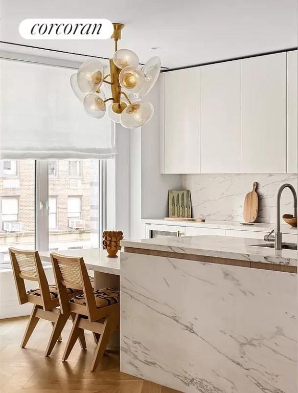 kitchen with sink, backsplash, a chandelier, and white cabinets