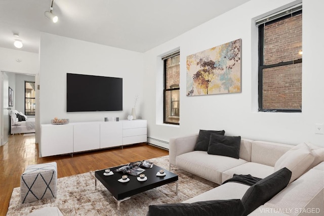 living room featuring hardwood / wood-style floors, rail lighting, and a baseboard radiator