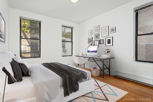 bedroom featuring a baseboard heating unit and wood finished floors