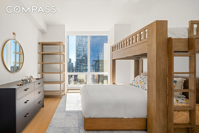 bedroom with expansive windows, a city view, and light wood finished floors