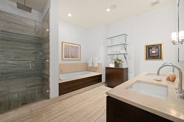 bathroom featuring a shower stall, a garden tub, double vanity, and recessed lighting