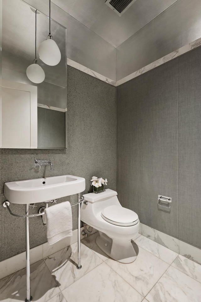 bathroom with toilet and marble finish floors