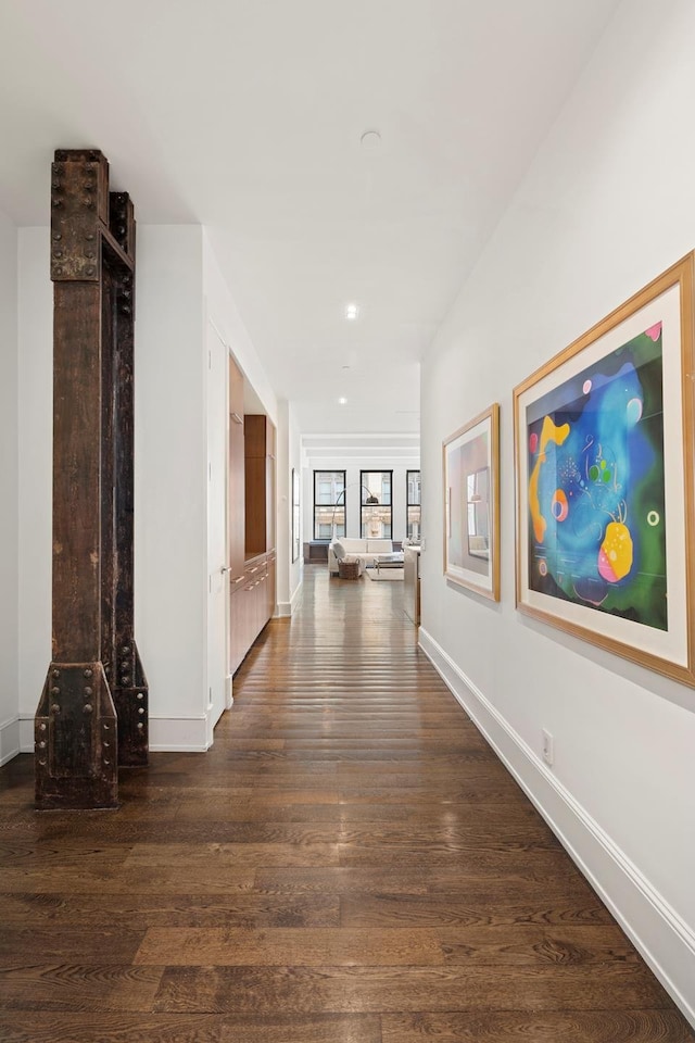 hall featuring dark wood-type flooring and baseboards