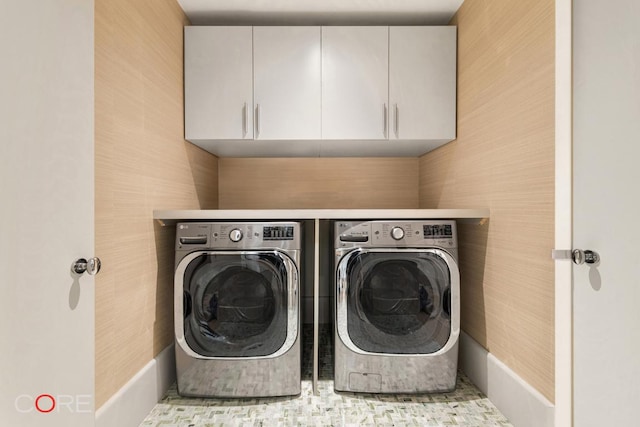 clothes washing area featuring washing machine and dryer and cabinets