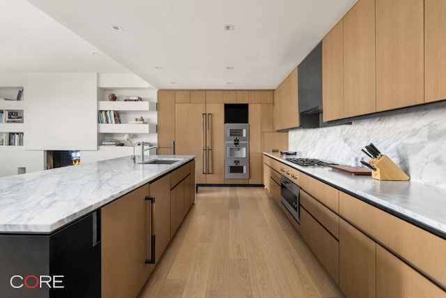 kitchen featuring sink, a large island, light hardwood / wood-style floors, stainless steel appliances, and wall chimney exhaust hood