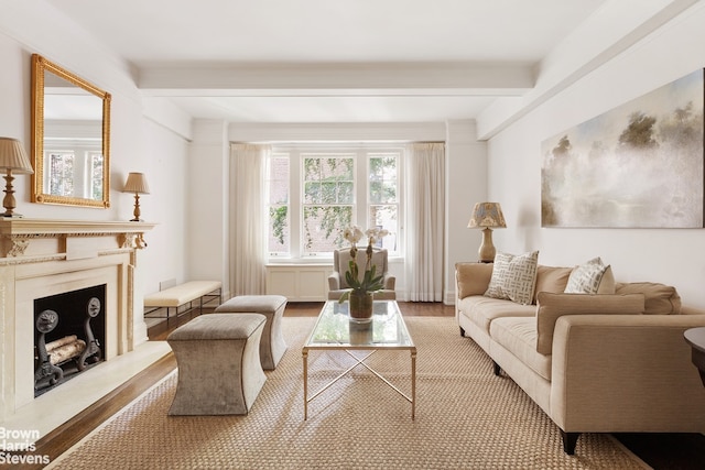 living area with a fireplace with raised hearth, beamed ceiling, and wood finished floors