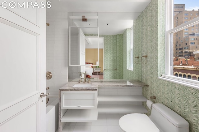 bathroom featuring a bathtub, toilet, vanity, and tile patterned flooring