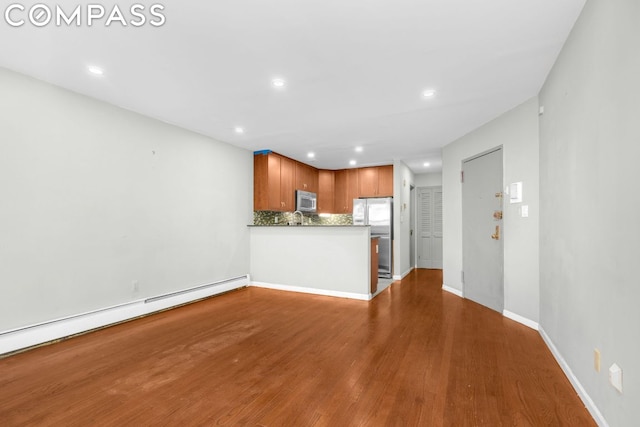 unfurnished living room featuring baseboard heating and hardwood / wood-style floors