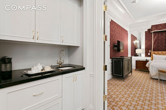 bar featuring white cabinetry, sink, and ornamental molding