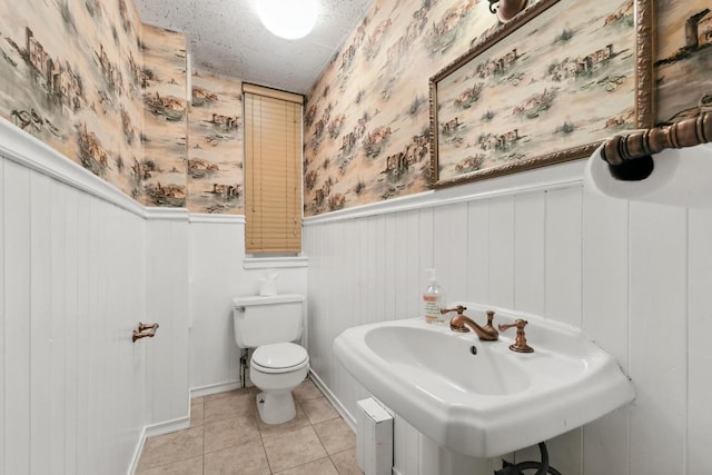 bathroom featuring toilet, tile patterned flooring, sink, and a textured ceiling