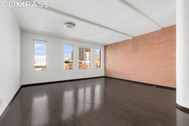 unfurnished room featuring dark wood-type flooring and brick wall