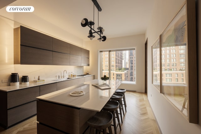 kitchen featuring pendant lighting, a breakfast bar area, a center island, and light parquet flooring