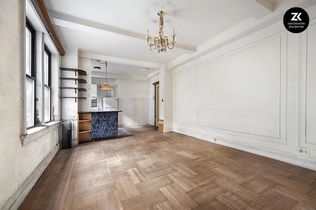 unfurnished living room featuring beamed ceiling, light parquet flooring, a wealth of natural light, and an inviting chandelier