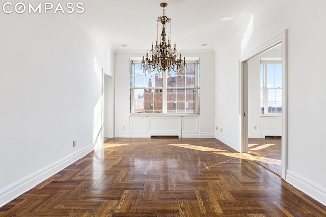 unfurnished dining area featuring plenty of natural light, dark parquet flooring, crown molding, and an inviting chandelier