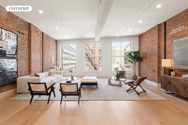 living area with light wood-type flooring, visible vents, and brick wall