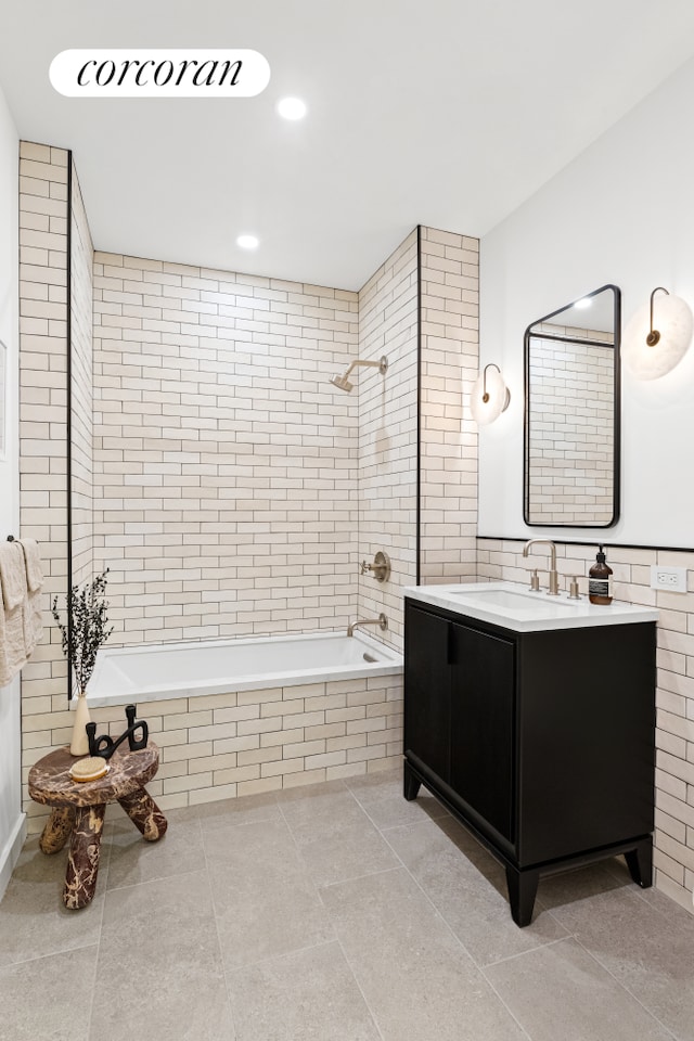 full bath featuring tiled shower / bath, vanity, tile patterned flooring, and tile walls