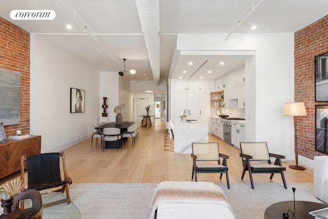 living room with recessed lighting, visible vents, light wood-style flooring, brick wall, and baseboards