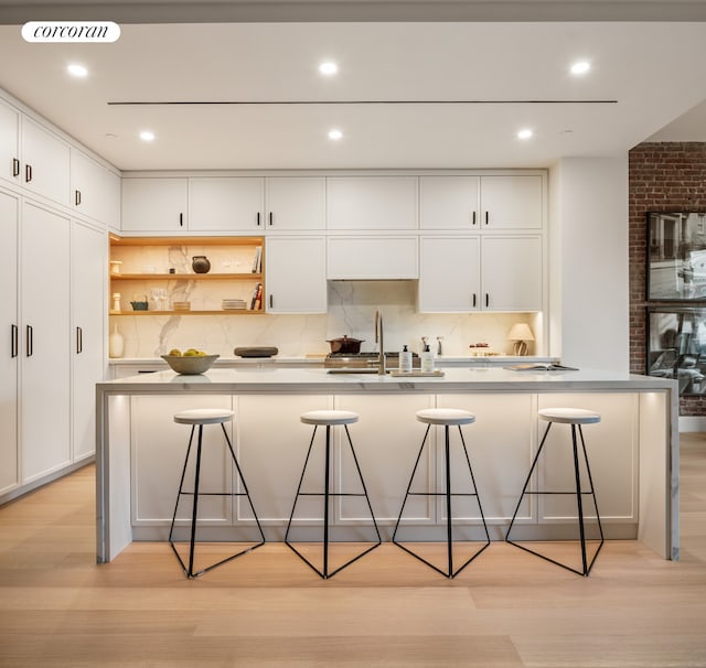 kitchen with open shelves, light wood finished floors, a sink, and white cabinetry