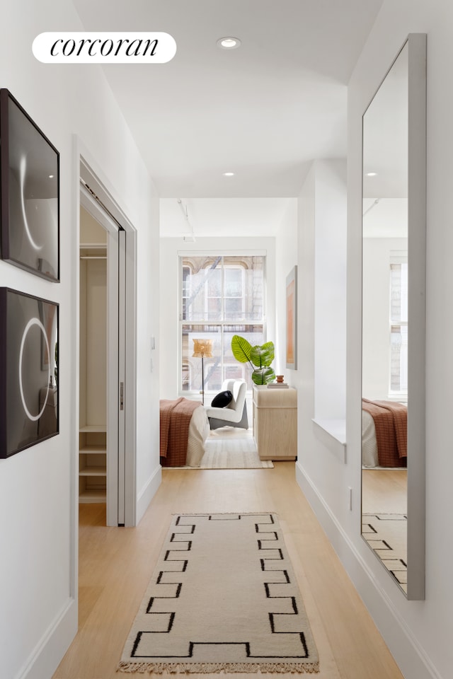 hall with light wood-style floors, baseboards, and recessed lighting