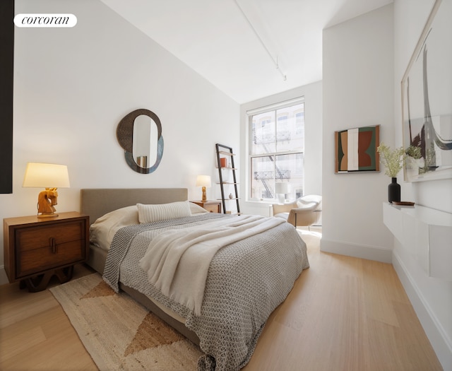 bedroom featuring light wood finished floors, baseboards, and rail lighting