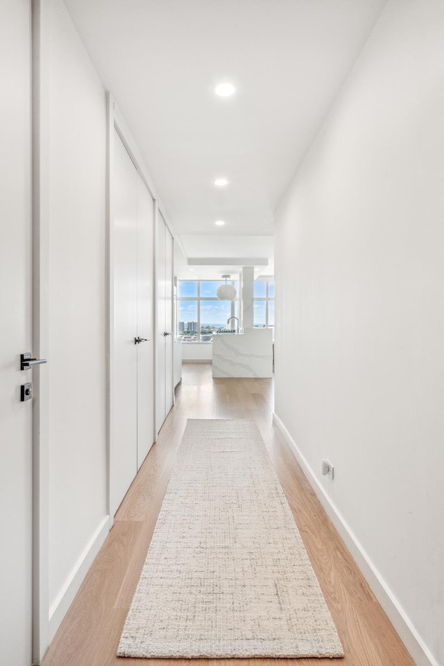 corridor featuring recessed lighting, light wood-style flooring, and baseboards